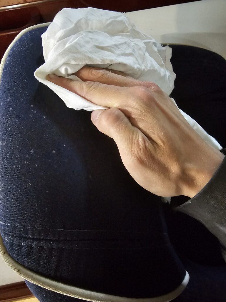 Mögelspray torkas av från mörk båtdyna med en vit trasa